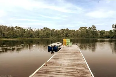 a dock with a boat on a lake at Pines Bay Waterfront cottage with Hot tub! in Kawartha Lakes