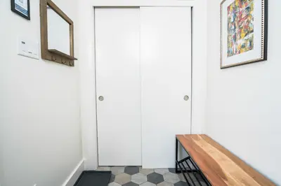 a hallway with white doors and a wooden bench at 