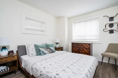 a bedroom with a bed and a desk and two windows at 