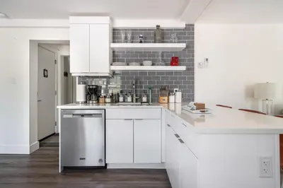 a kitchen with white cabinets and a tile wall at 