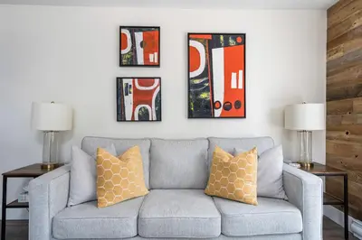 a living room with a gray couch and four paintings at 