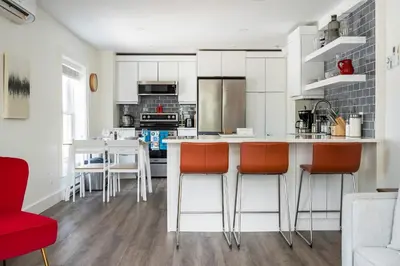 a kitchen with white cabinets and orange bar stools at 