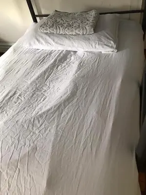 an unmade bed with white sheets and a pillow at Zen Hostel in Toronto