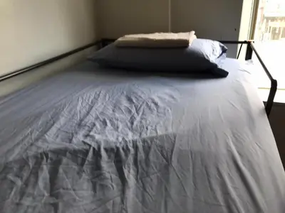 a bed in a bedroom with a white bedsheet at Zen Hostel in Toronto