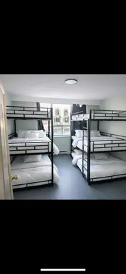 a room with three bunk beds with white sheets at Zen Hostel in Toronto