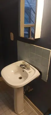 a white sink in a bathroom with a window at Zen Hostel in Toronto