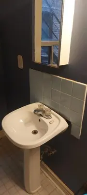 a white sink in a bathroom with a window at Zen Hostel in Toronto