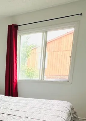 a bedroom window with a red curtain and a bed at ComfyRoom in Toronto