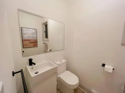 a white bathroom with a toilet and a mirror at Beach House in Niagara in Wainfleet