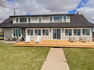 a house with a large wooden deck with chairs at Beach House in Niagara in Wainfleet