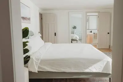 a white bedroom with a large bed with white sheets at Beach House in Niagara in Wainfleet
