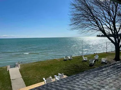 a group of chairs sitting on the grass near the water at Beach House in Niagara in Wainfleet