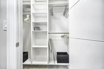 a closet with white shelves and a refrigerator at Charming and Luxurious 2BR+1Bath Guest Suite in Toronto
