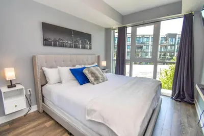 a bedroom with a large white bed with blue pillows at PET FRIENDLY CONDOS at FRIDAY HARBOUR in Innisfil