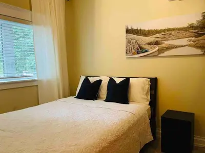 a bedroom with a bed and a painting on the wall at SouthLake Cottage on The Lake. in Washago