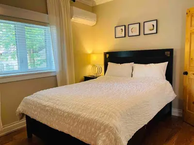 a bedroom with a large bed and a window at SouthLake Cottage on The Lake. in Washago