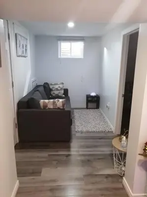 a living room with a black couch in a room at Cozy nest basement unit in Hamilton