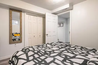 a bedroom with a bed with a black and white comforter at Cozy nest basement unit in Hamilton