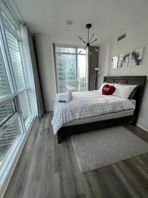 a bedroom with a bed and a large window at Prestigious 2-Bdrm Condo - across from Scotiabank Arena in Toronto