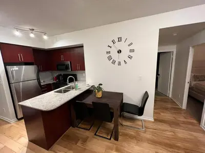 a kitchen with a table and a clock on the wall at Prestigious 2-Bdrm Condo - across from Scotiabank Arena in Toronto
