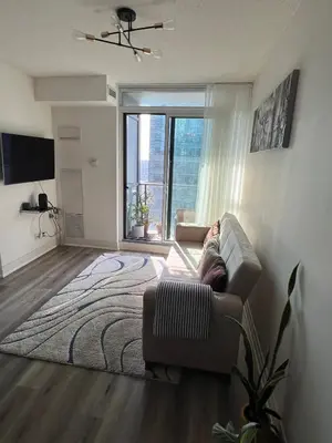 a living room with a couch and a large window at Prestigious 2-Bdrm Condo - across from Scotiabank Arena in Toronto
