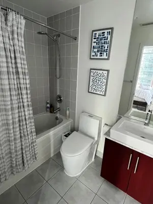 a bathroom with a toilet and a tub and a sink at Prestigious 2-Bdrm Condo - across from Scotiabank Arena in Toronto