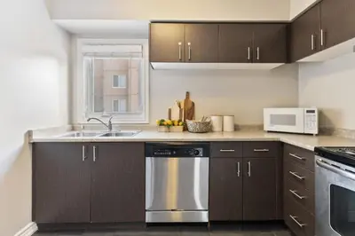 a kitchen with brown cabinets and a stainless steel dishwasher at Blue Mountain Chalet Condo with Amazing Location in Blue Mountains