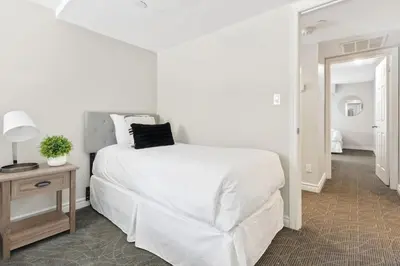 a white bedroom with a white bed and a table at Blue Mountain Chalet Condo with Amazing Location in Blue Mountains