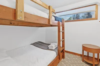 two bunk beds in a room with a table and a chair at Large Chalet for up to 16 ppl close to mountains in Blue Mountains
