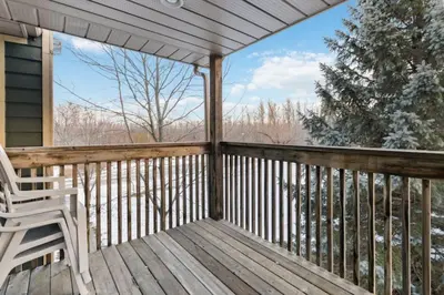 a deck with a chair and a view of the woods at Four Peaks - Unit 40B in Collingwood