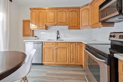 a kitchen with wooden cabinets and a sink and a table at Four Peaks - Unit 40B in Collingwood