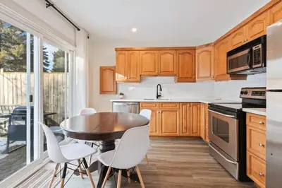 a kitchen with wooden cabinets and a table and chairs at Four Peaks - Unit 40B in Collingwood