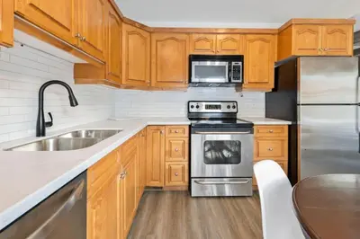a kitchen with wooden cabinets and stainless steel appliances at Four Peaks - Unit 40B in Collingwood