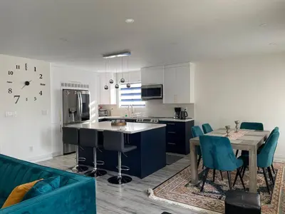 a kitchen and living room with a table and blue chairs at Mama Gol in Richmond Hill