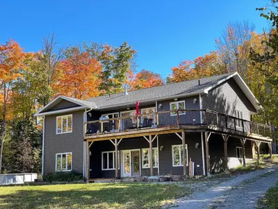 a large black house with a porch and deck at Mountain House in the Heart of Haliburton, Mins to Lake in Haliburton