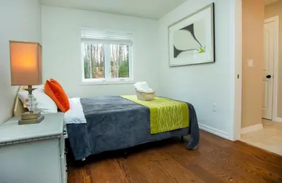 a bedroom with a bed and a table and a window at Mountain House in the Heart of Haliburton, Mins to Lake in Haliburton