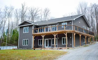 a house with a deck on the side of it at Mountain House in the Heart of Haliburton, Mins to Lake in Haliburton