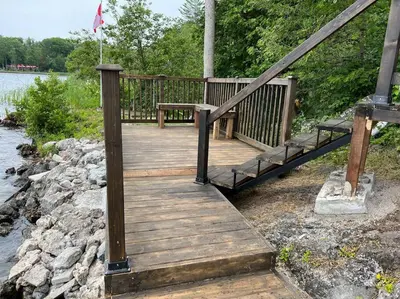a wooden bridge over a river with a flag on it at Marmora Hideaway - Lake front in Marmora