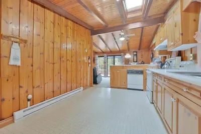 a large kitchen with wooden walls and wooden cabinets at Rustic cottage on Canal Lake in Carden