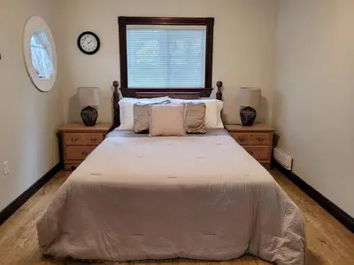 a bedroom with a large bed with two dressers and a window at Rustic Pines Waterfront Cottage *CLEAR WATER* in Fenelon Falls