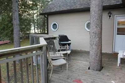 a deck with chairs and a grill on a house at Rustic Pines Waterfront Cottage *CLEAR WATER* in Fenelon Falls