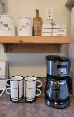 a coffee maker and three coffee cups on a shelf at Rustic Pines Waterfront Cottage *CLEAR WATER* in Fenelon Falls