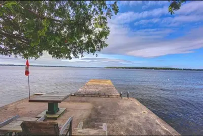 a dock with a picnic table on the water at Rustic Pines Waterfront Cottage *CLEAR WATER* in Fenelon Falls