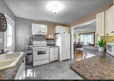 a large kitchen with white appliances and a sink at Rustic Pines Waterfront Cottage *CLEAR WATER* in Fenelon Falls