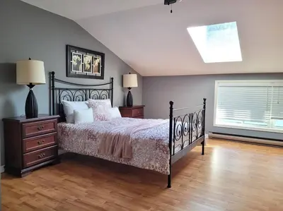 a bedroom with a black bed and a window at Whispering Pines Riverside Retreat in Coboconk