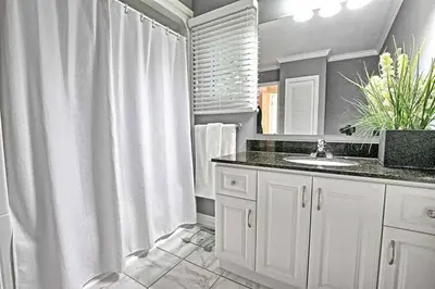 a white bathroom with a sink and a shower at Whispering Pines Riverside Retreat in Coboconk