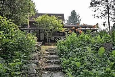 a garden with a stone path leading to a house at Whispering Pines Riverside Retreat in Coboconk