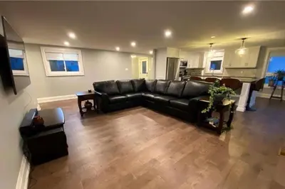 a living room with a black couch and a kitchen at Chemong Lake Waterfront Cottage☆privateboatlaunch in Lakefield