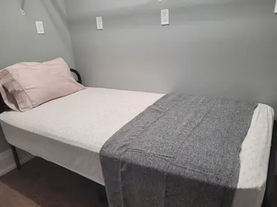 a bed with a gray blanket and a pillow at Chemong Lake Waterfront Cottage☆privateboatlaunch in Lakefield
