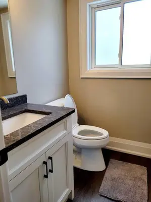 a bathroom with a toilet and a sink and a window at Chemong Lake Waterfront Cottage☆privateboatlaunch in Lakefield